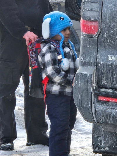 A small child with a bunny hat and a Spiderman backpack